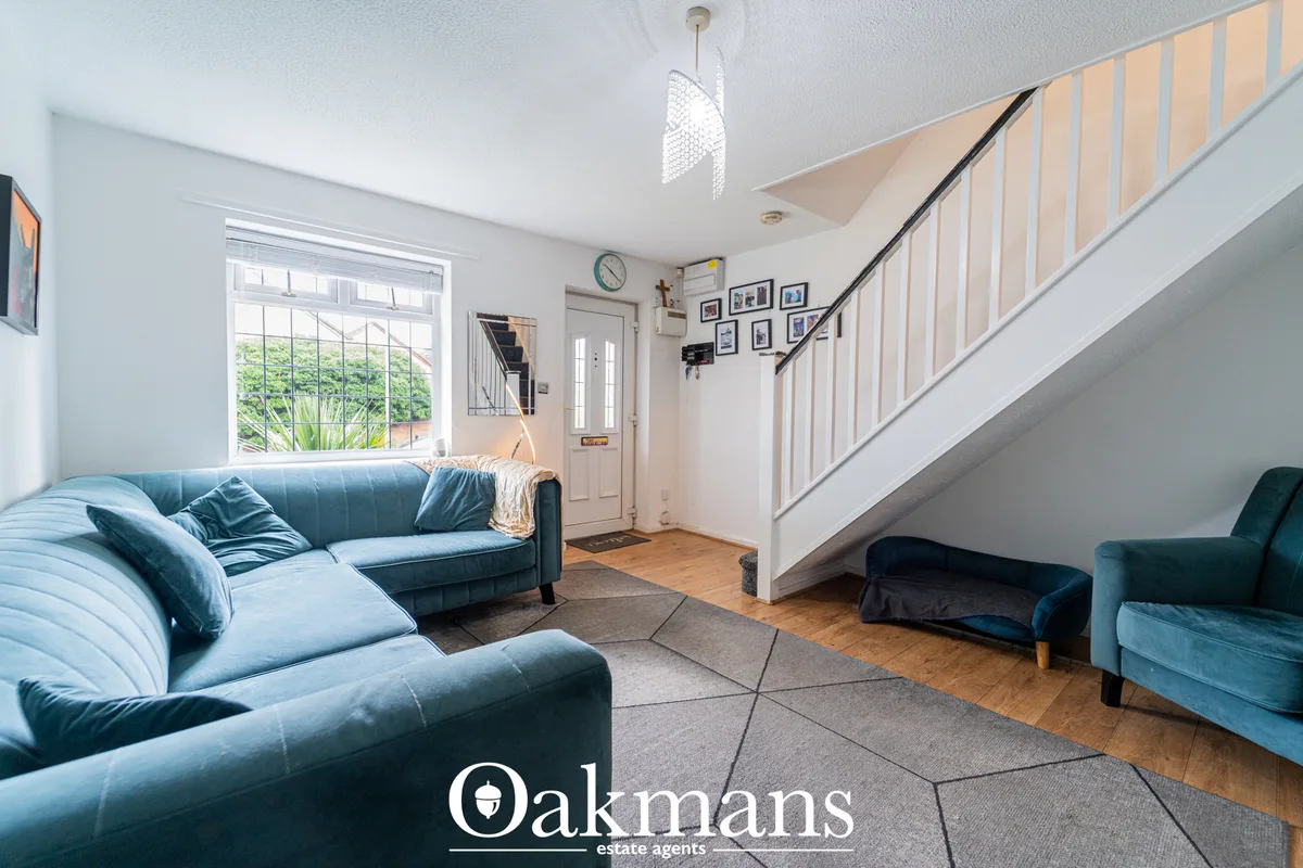 Bright living room with blue leather corner sofa, wooden flooring, staircase with white spindles, pendant light, and lar