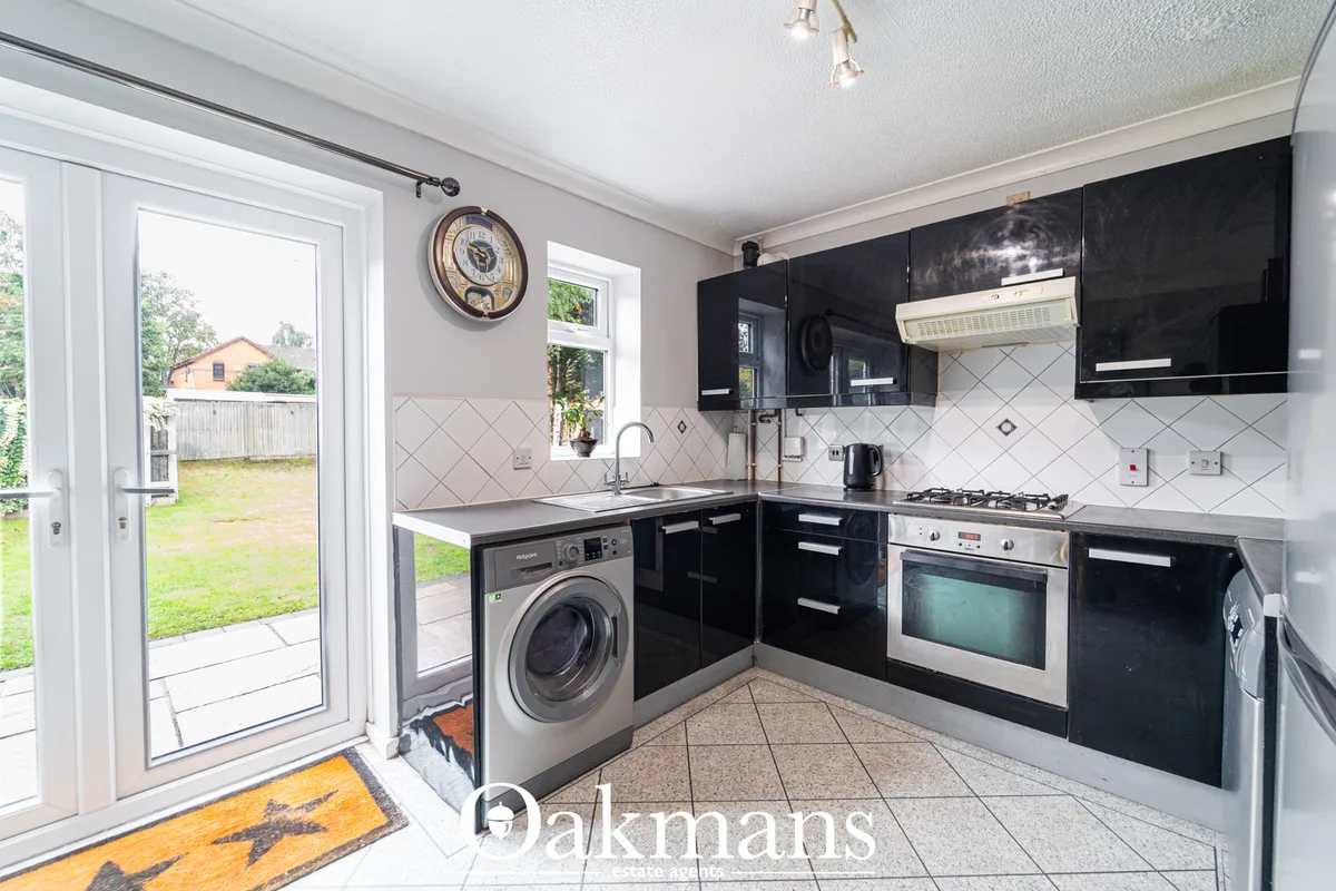 Modern kitchen with black gloss units, white diamond-patterned splashback, stainless steel appliances, washing machine, 