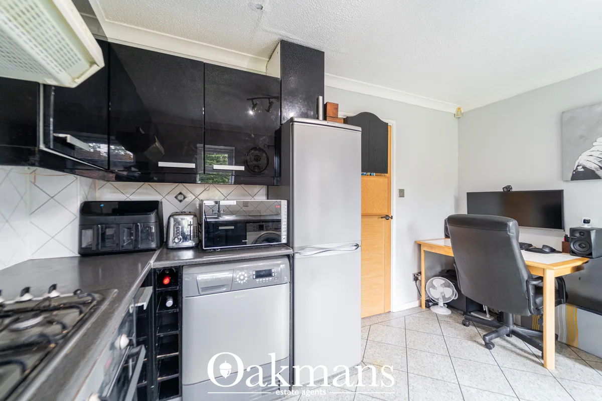 Open-plan kitchen and dining area with black gloss wall units, white worktops, integrated appliances, and reception room