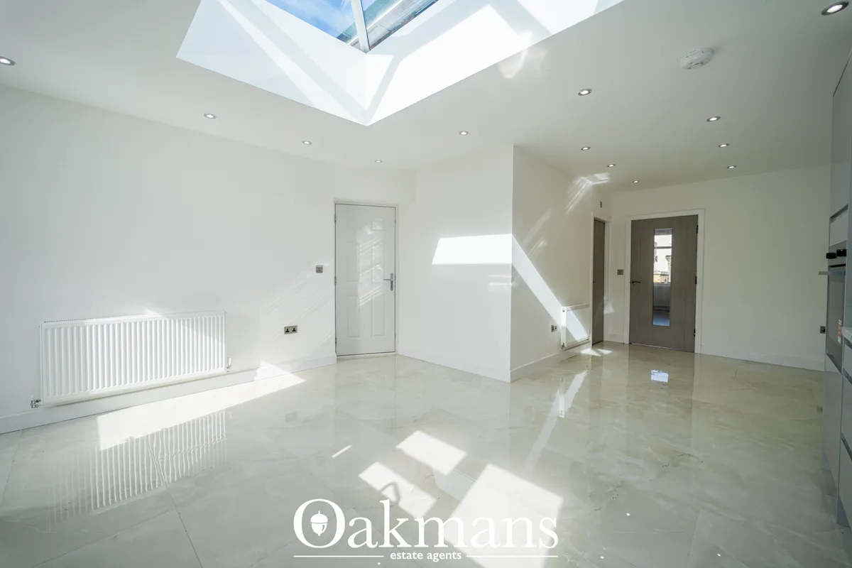 Bright modern hallway with polished concrete flooring, skylight, white walls, radiator, multiple doors and recessed ligh