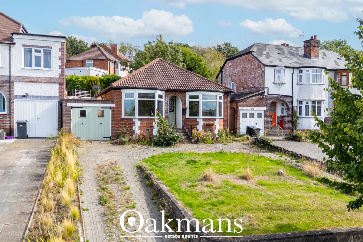 Red brick bungalow with white trim, driveway and overgrown front garden, neighbouring period homes visible