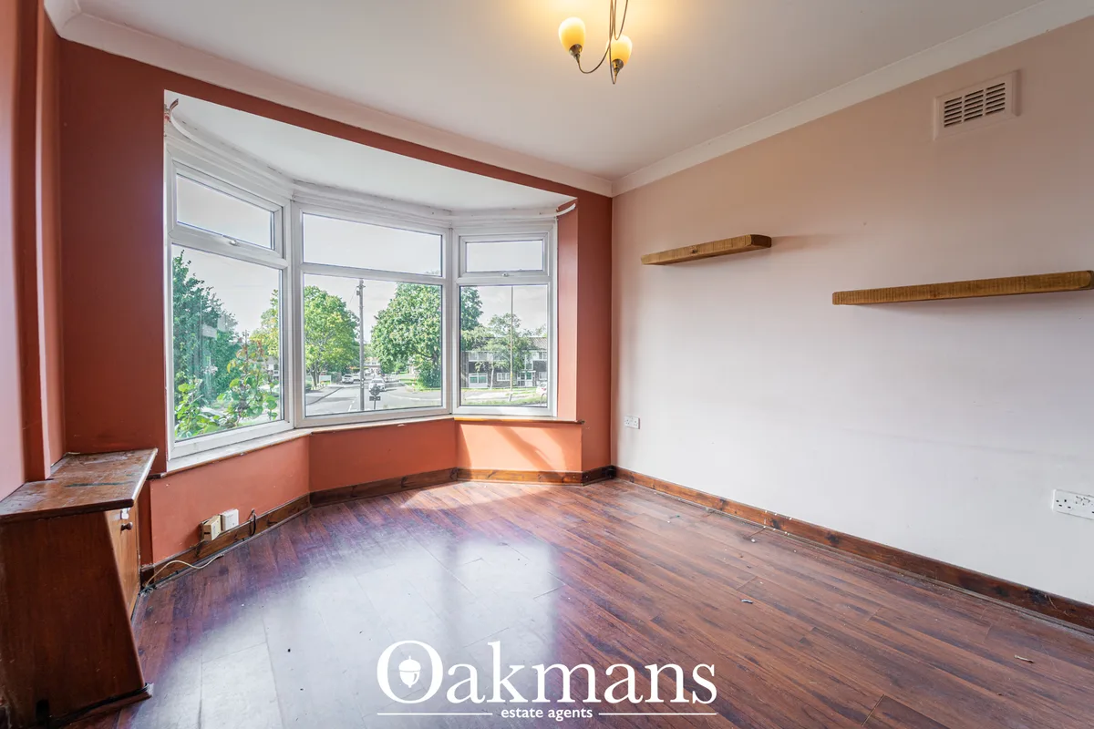Bright living room with curved bay window, terracotta accent wall, wooden flooring, wooden shelving and ceiling light fi