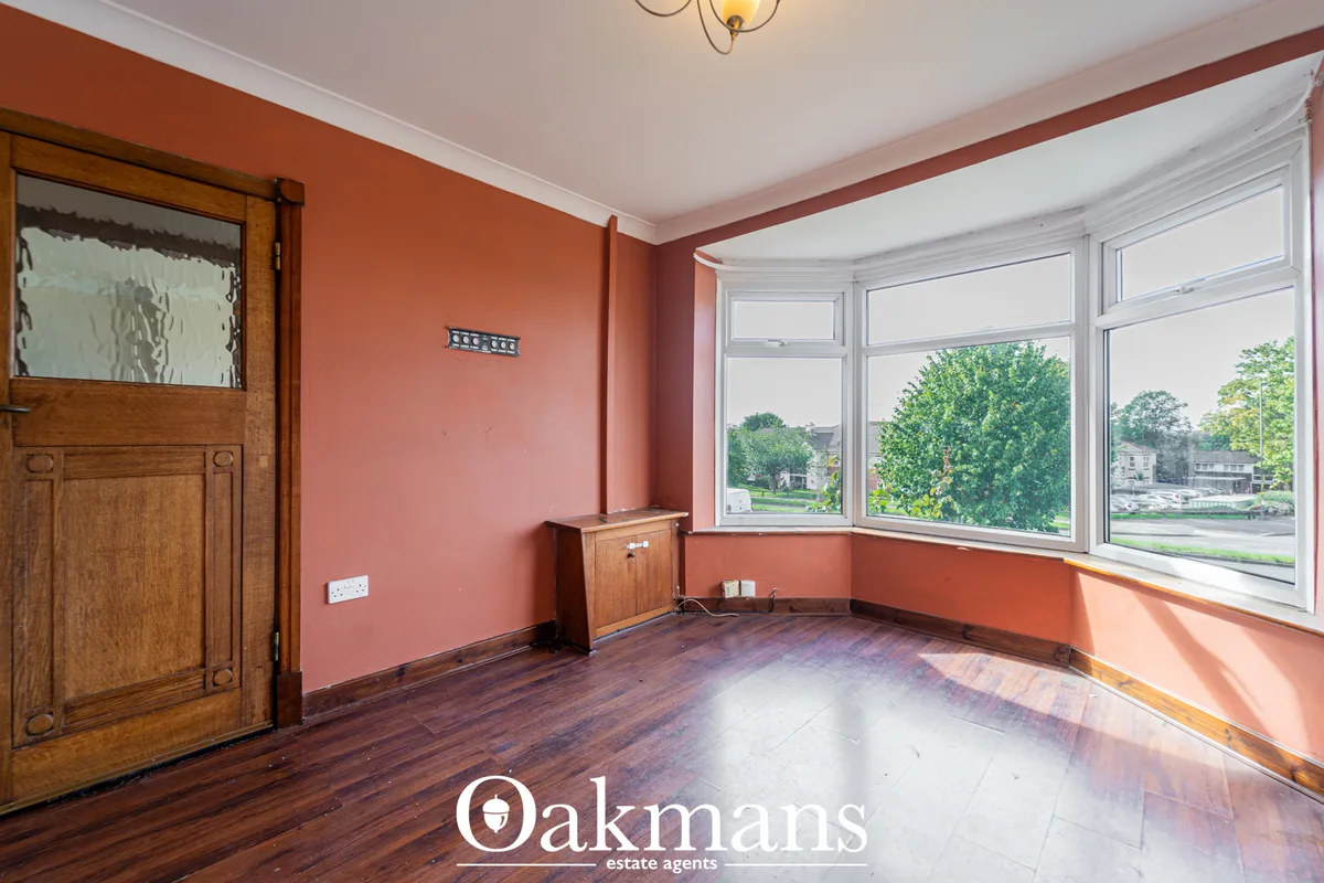 Bright living room with coral-pink walls, wooden flooring, bay windows overlooking gardens, wooden door and ceiling pend
