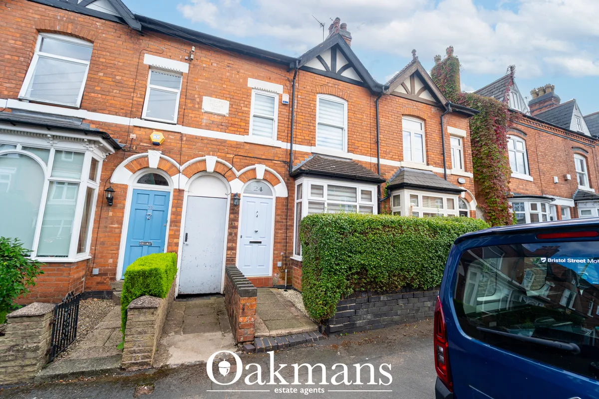 Red brick Victorian terraced houses with white-framed windows, blue and white doors, decorative gables and hedging