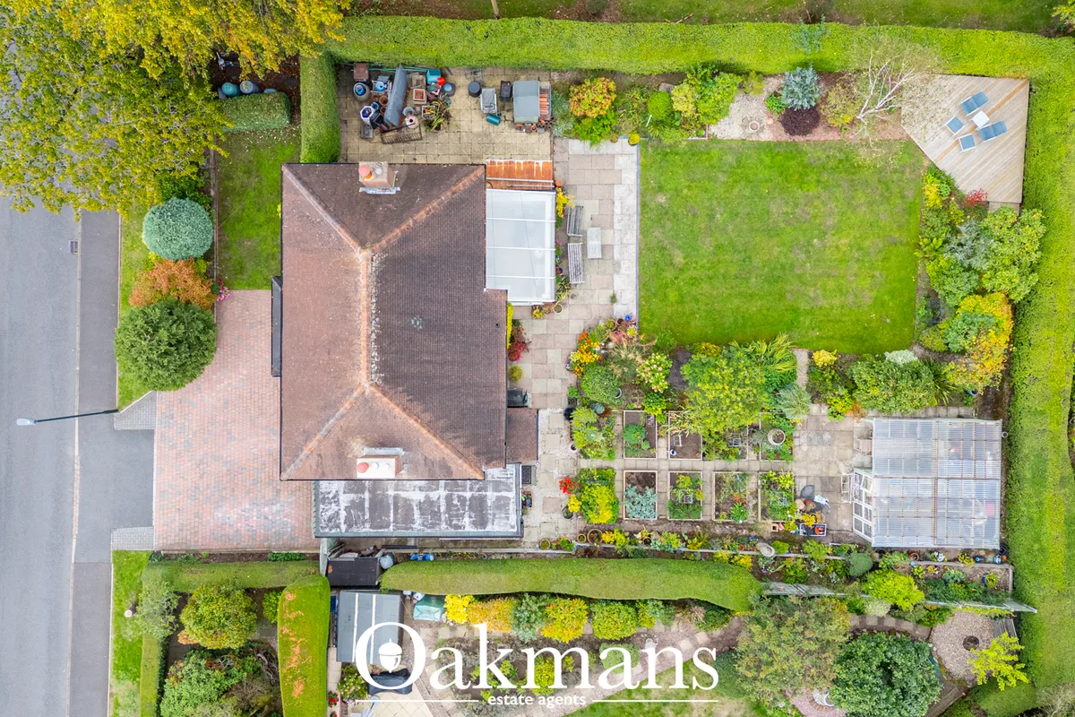 Overhead aerial view of brick residential property with pitched roof, patio, extensive gardens, greenhouse, planted bord