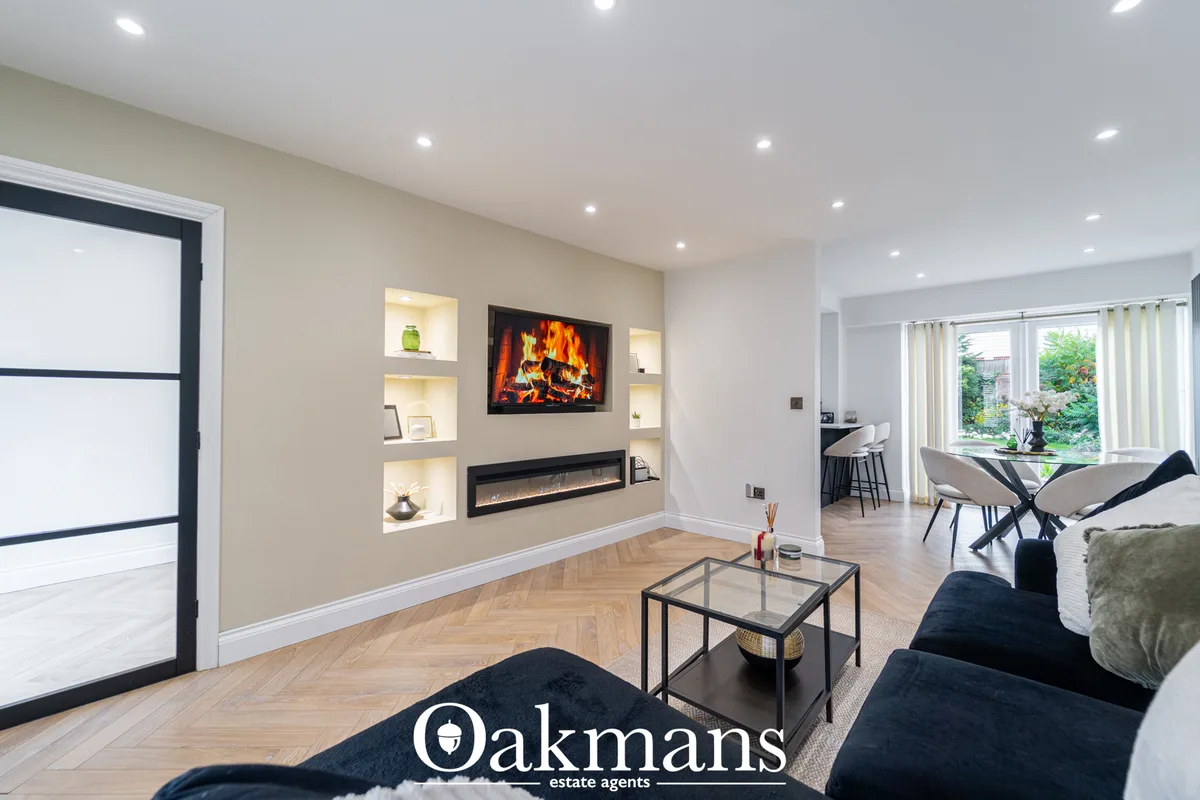 Contemporary living room with fireplace feature wall, built-in shelving, wall-mounted TV, black sofa, glass coffee table