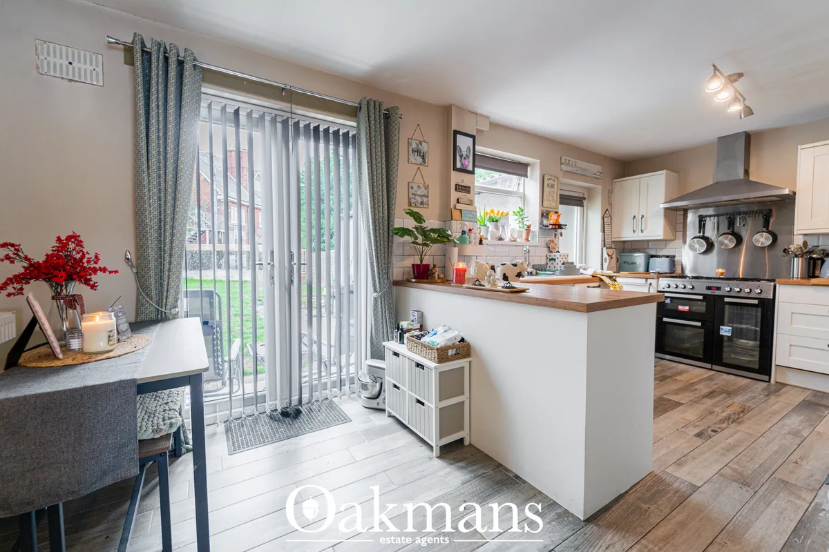 Modern open-plan kitchen with white units, wood worktops, black double oven, island with storage, and patio doors overlo