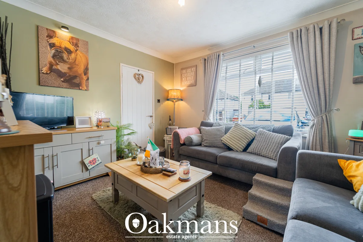 Bright living room with grey sofa, patterned cushions, wooden coffee table, yellow walls, large windows with grey curtai
