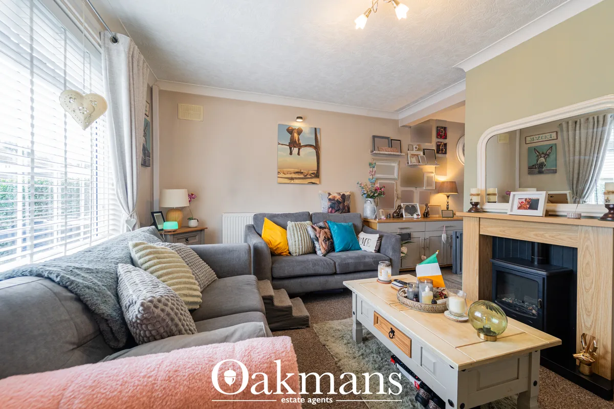 Spacious living room with grey sofas, fireplace, wooden furniture, yellow and blue cushions, wall art, and large windows