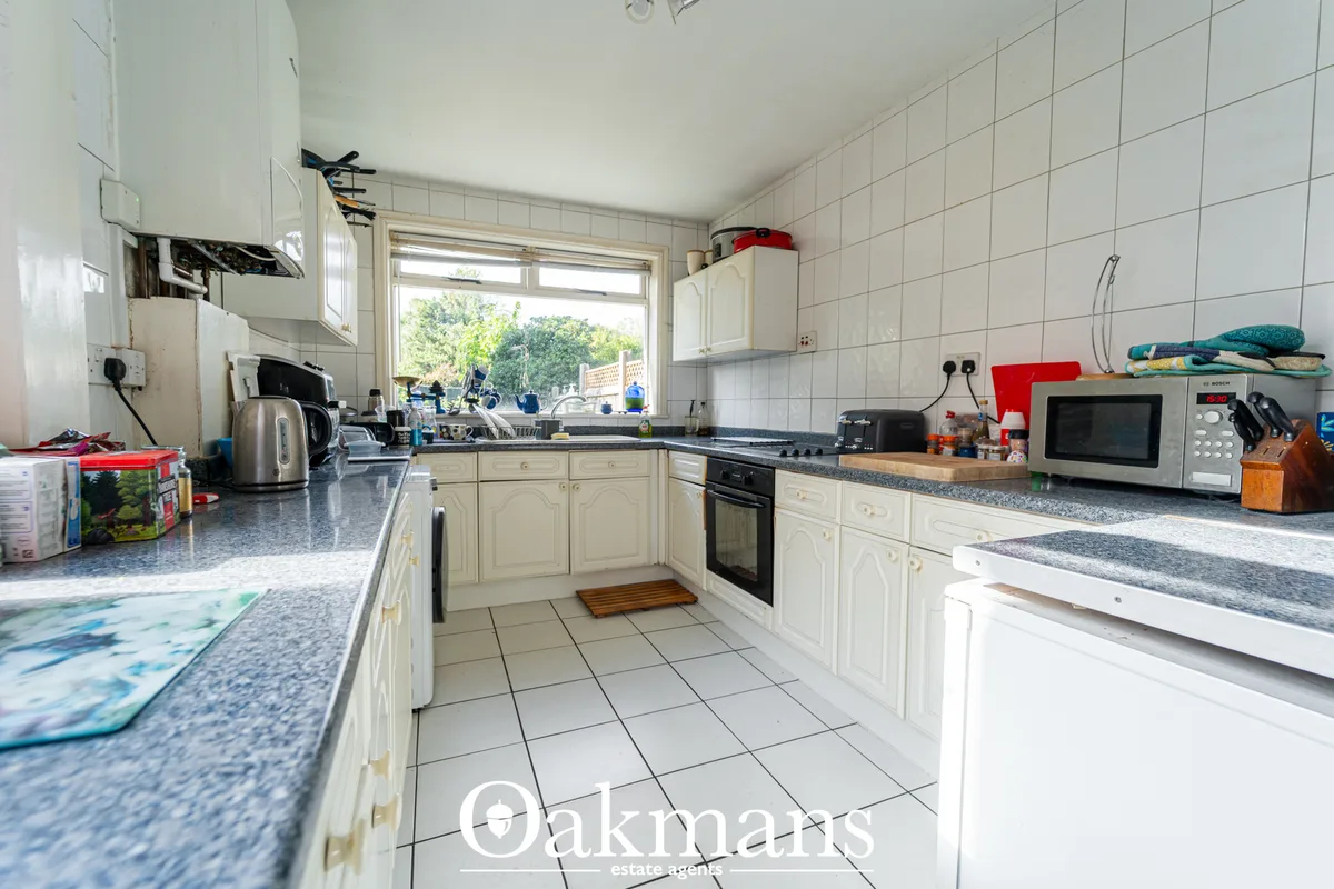 Cream fitted kitchen with granite worktops, white tile walls, double oven, microwave, kettle and various appliances. Lar
