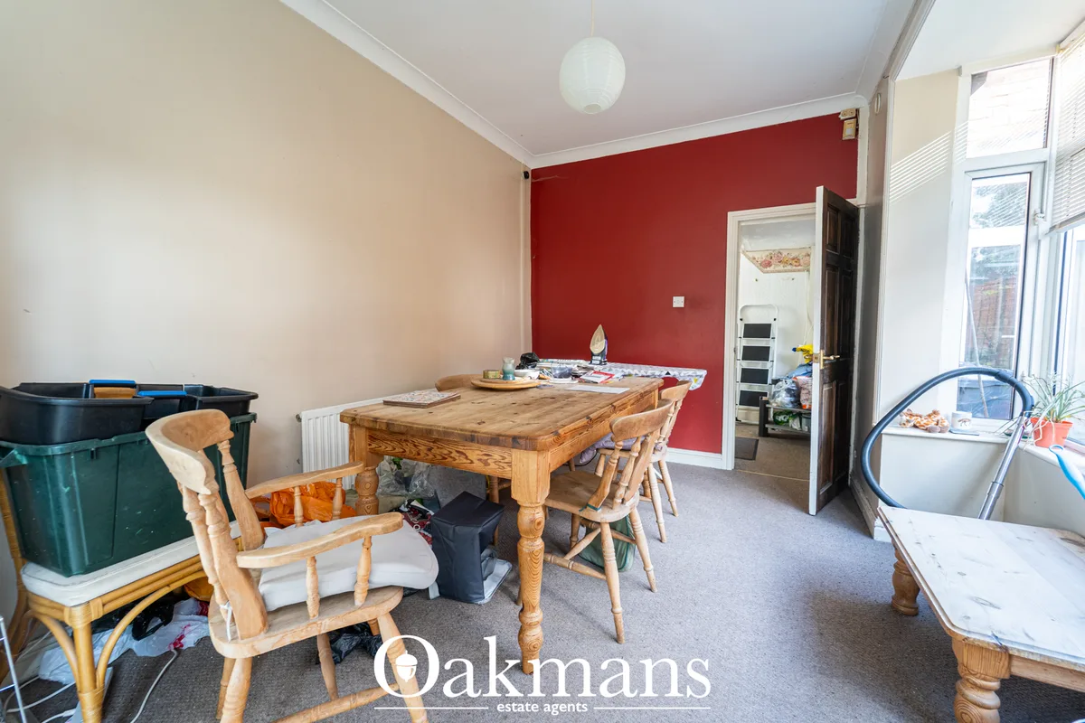 Dining room with wooden table and chairs, red accent wall, radiator, and doorway to kitchen area with white ceiling and 