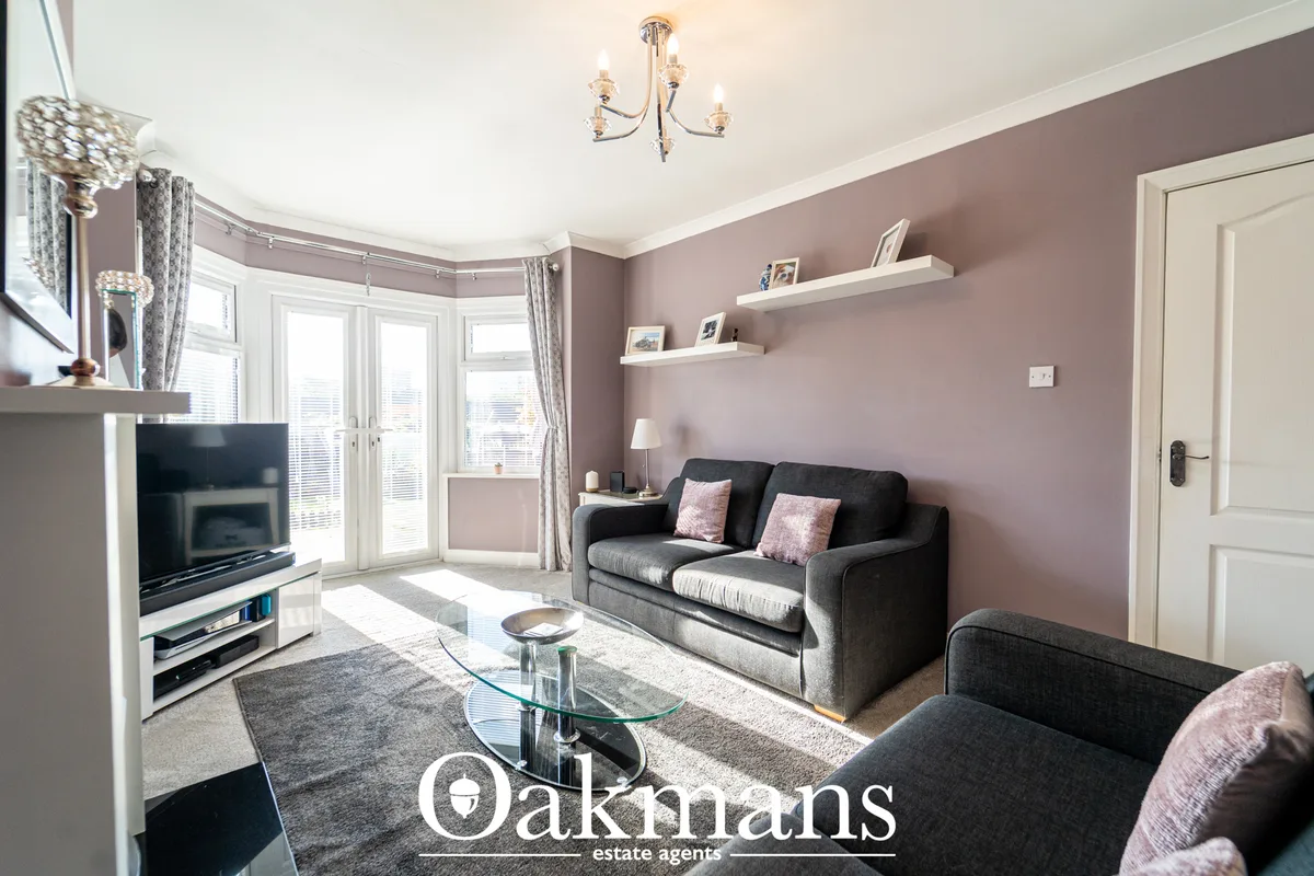 Spacious living room with mauve walls, grey sofas, fireplace with TV, patio doors, white ceiling and modern lighting