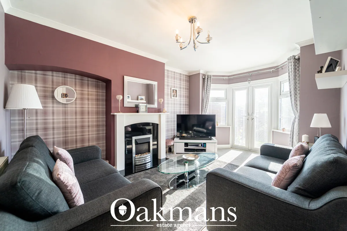 Spacious living room with dual grey sofas, fireplace with black insert, TV, plaid feature walls, bay windows with shutte