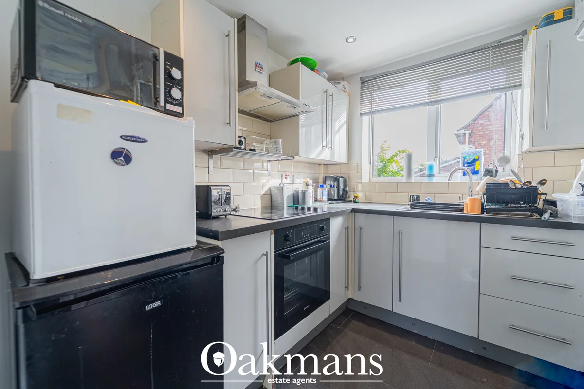 Modern fitted kitchen with white units, dark worktops, black built-in oven, stainless steel range hood, white refrigerat