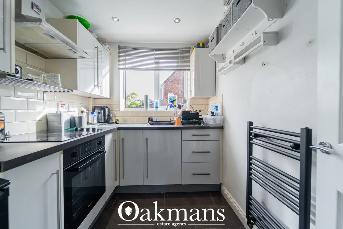 Modern fitted kitchen with grey cabinetry, black worktops, white subway tile splashback, built-in oven, window with blin
