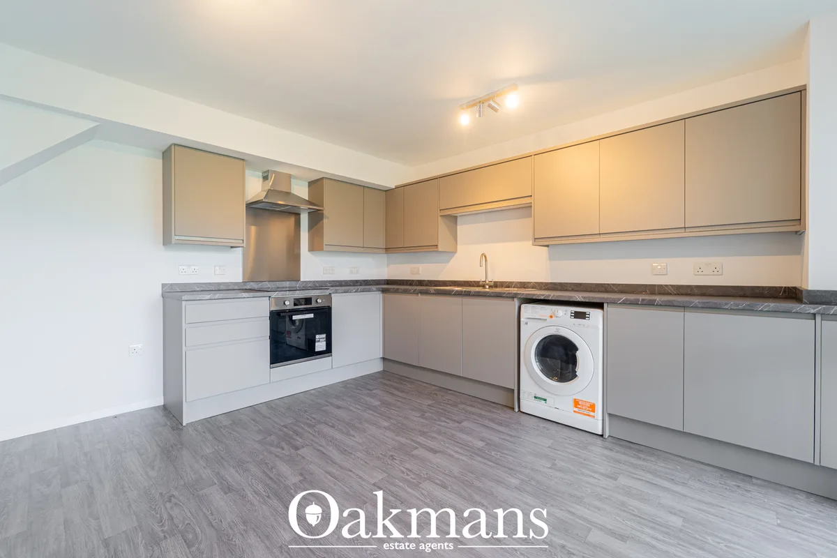 Modern fitted kitchen with white and beige units, dark granite worktops, built-in oven, hob, extractor hood, white washi