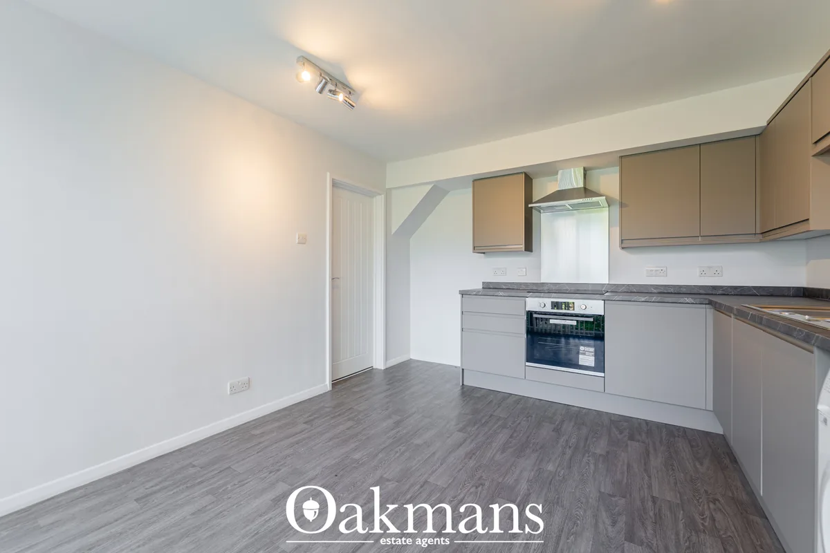 Modern fitted kitchen with grey base units, beige wall units, built-in oven and range hood, dark worktops, wood-effect f