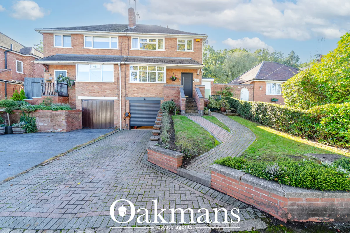 Two-storey red brick house with driveway, garage, landscaped front garden and hedging