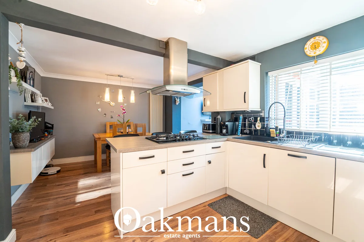 Modern fitted kitchen with cream units, wooden worktops, gas hob, integrated appliances and breakfast bar, teal accent w