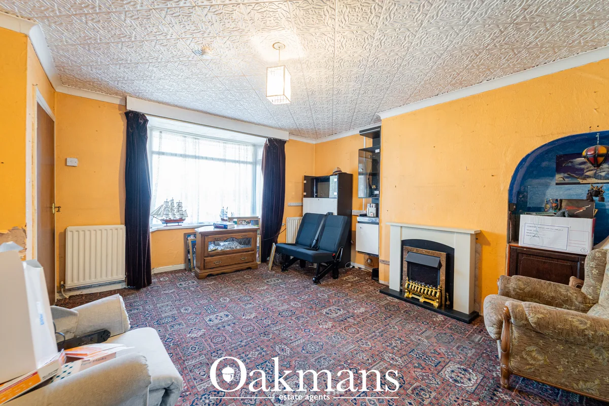 Bright orange living room with blue curtains, fireplace, wooden furniture, patterned carpet, and decorative ship models 