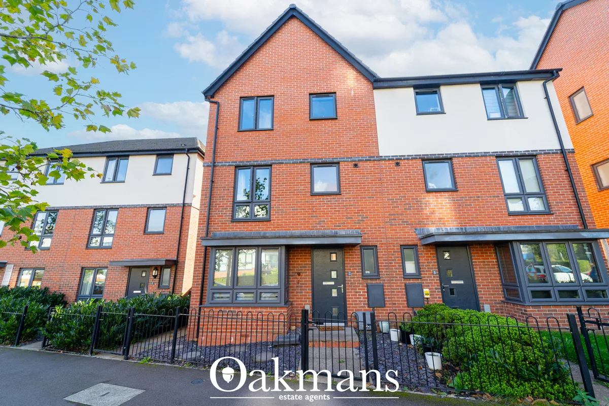 Modern red-brick residential townhouses with white rendered sections, pitched roofs, black framed windows, and black iro
