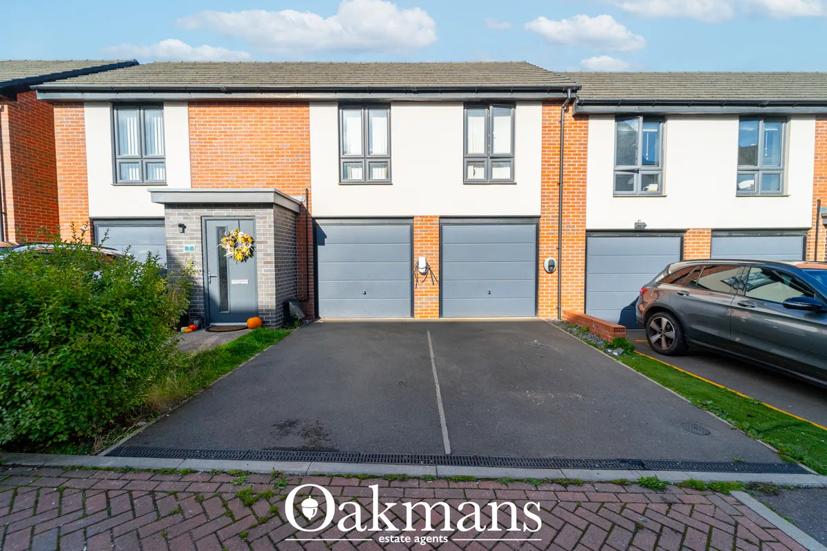 Modern brick and render townhouse with double garage, driveway, and parked vehicle under blue sky