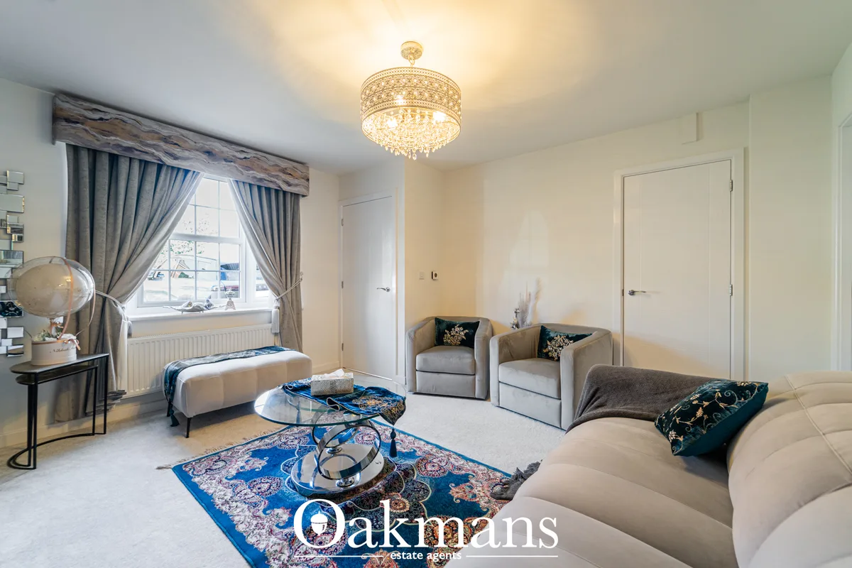 Elegant living room with cream sofa, two grey armchairs, blue patterned rug, ornate ceiling light, grey curtains with wo