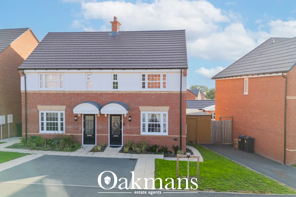 Modern red brick semi-detached house with dark grey roof, white-framed windows, twin black doors with blue canopies, dri