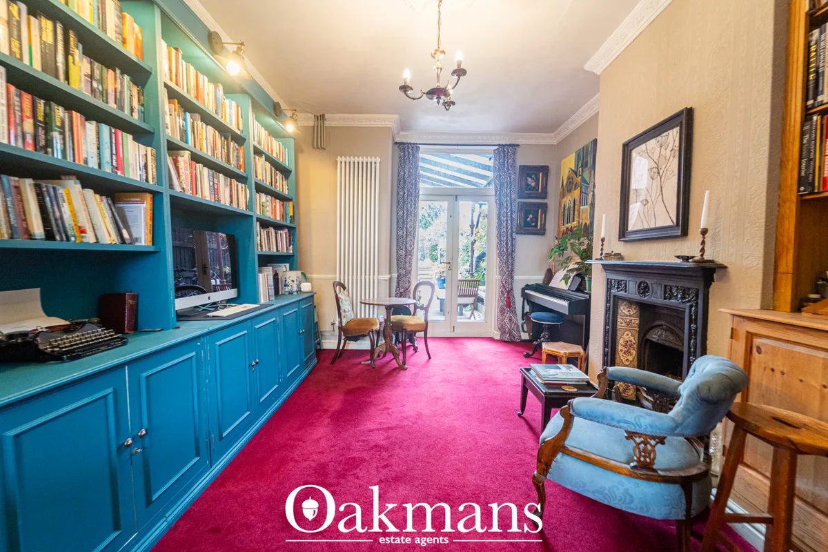 Elegant study with turquoise built-in bookshelves, fireplace, piano, pink carpet, period features and garden access
