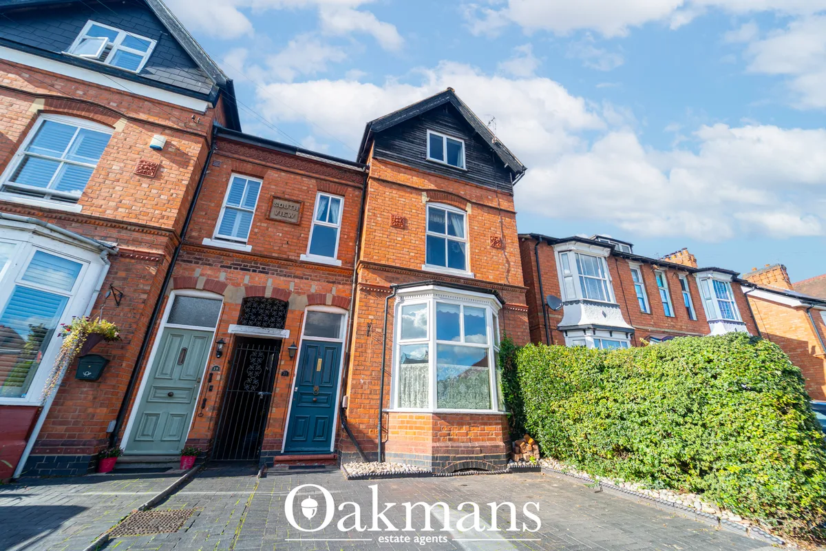 Terraced Victorian brick townhouses with blue sash windows, blue-black roof, ivy-covered boundary wall and paved forecou