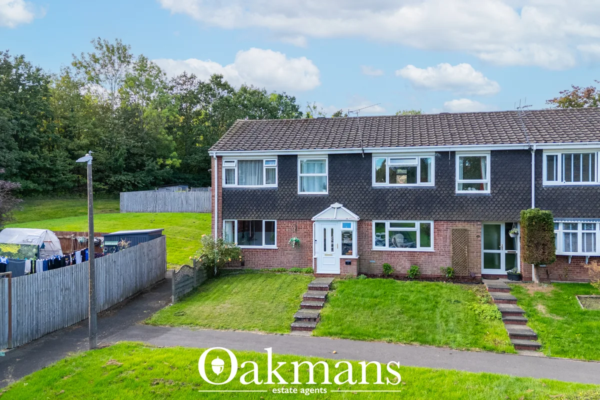 Brick semi-detached house with dark roof tiles, white-framed windows, central entrance porch, manicured front lawn and s