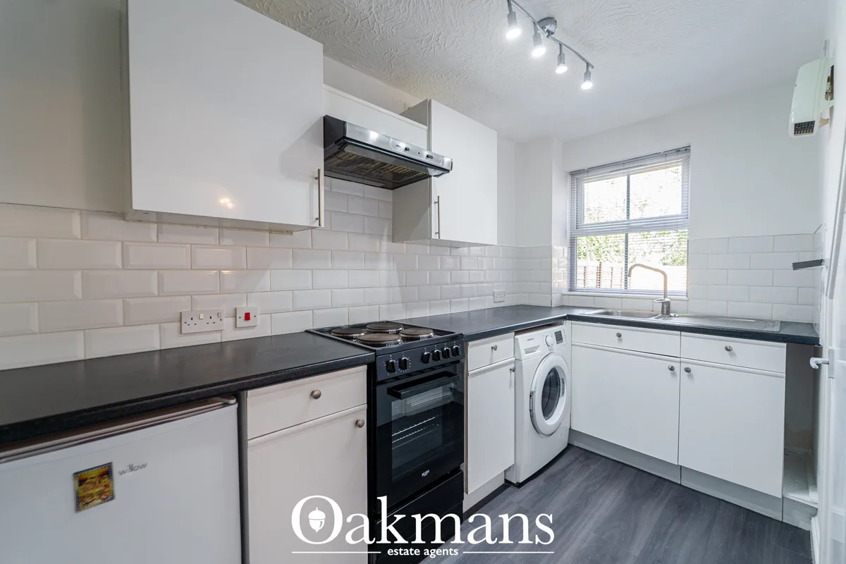 Modern white fitted kitchen with black granite worktops, subway tile splashback, black range cooker, washing machine, an
