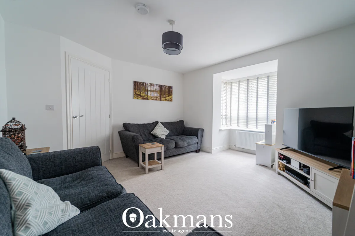 Spacious living room with two dark grey sofas, wooden coffee table, pendant light, large windows with shutters, TV stand