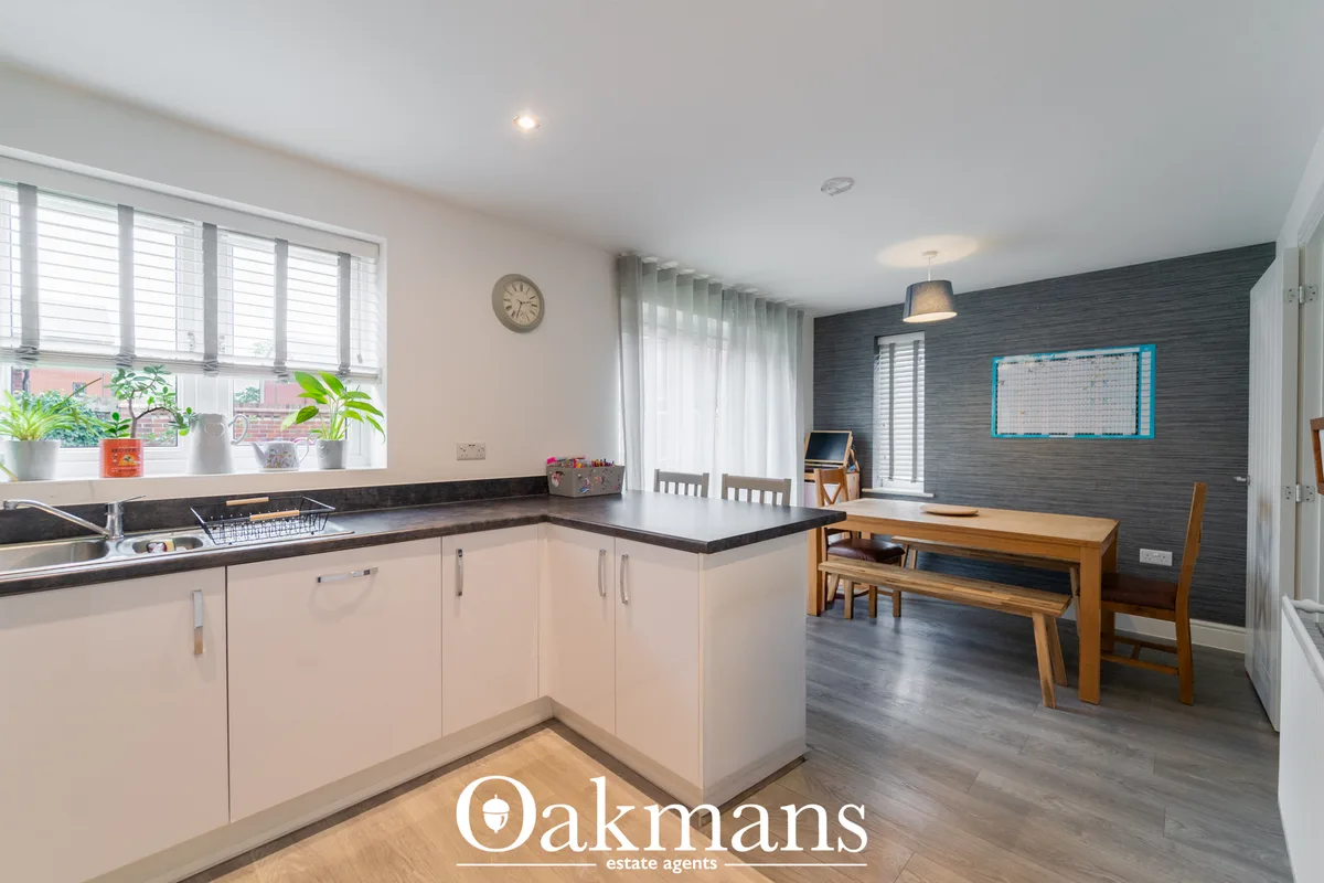 Modern open-plan kitchen with white cabinetry, black granite worktops, stainless steel appliances and breakfast bar