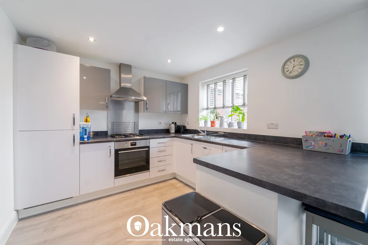 Modern fitted kitchen with white units, dark granite worktops, gas hob, integrated appliances and breakfast bar