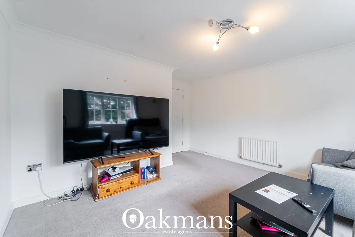Bright living room with wall-mounted flat-screen TV, wooden media unit, black coffee table, grey sofa, white radiator an