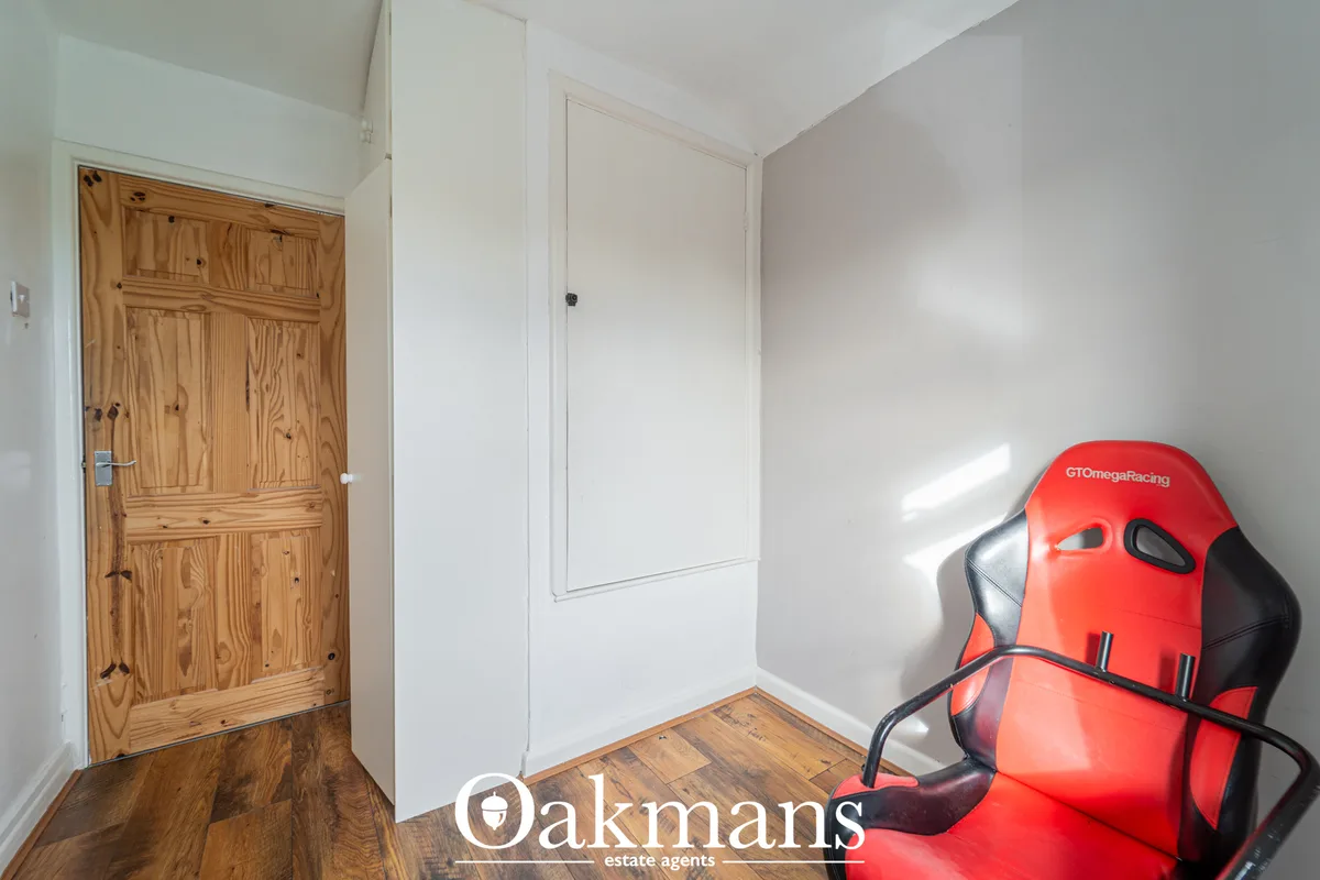 Bright hallway with wooden pine door, white built-in storage, wooden flooring, and red gaming chair
