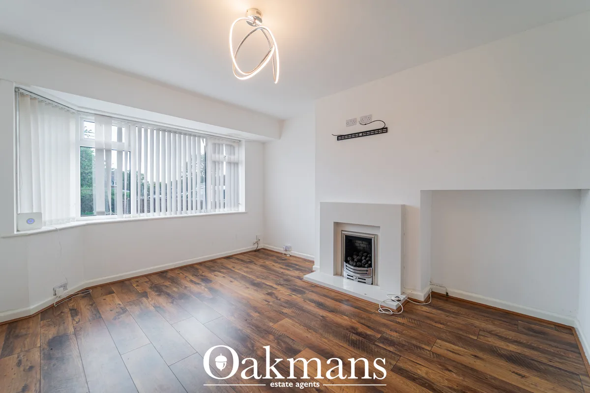 Spacious living room with wooden flooring, white walls, modern ceiling light, fireplace with white surround, large verti
