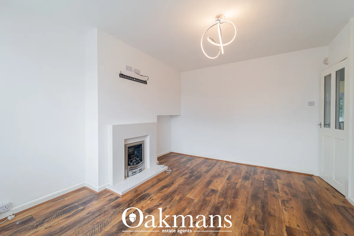 Spacious living room with wooden flooring, white walls, fireplace with chrome surround, modern ceiling light, and white 