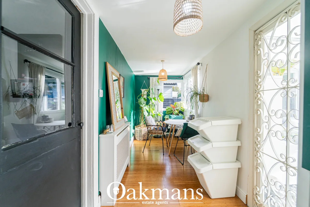 Bright hallway with wooden flooring, white storage baskets, decorative door with ornate grille, leading to teal-painted 