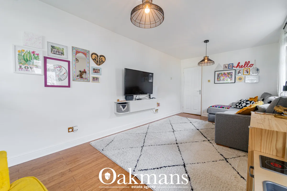Bright living room with grey sofa, wall-mounted TV, geometric patterned rug, wooden flooring and decorative wall art