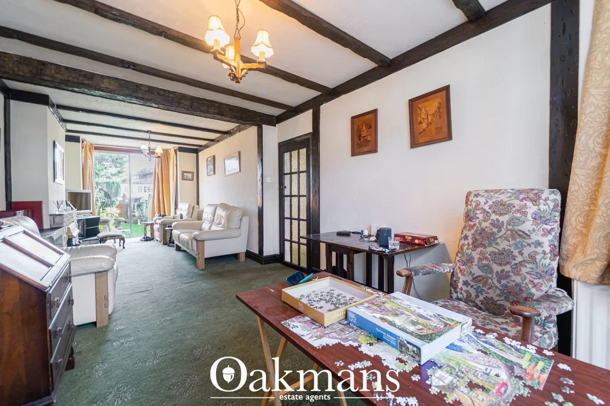 Spacious living room with exposed wooden beams, cream upholstered furniture, puzzles on table, dark timber doors, wall a