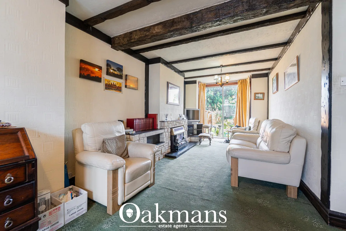 Spacious living room with cream furnishings, fireplace, exposed beam ceiling, patio doors to garden, and period wooden f