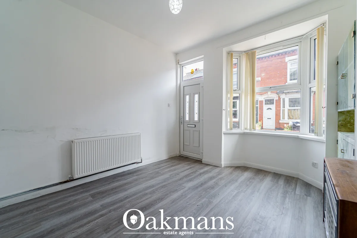 Bright hallway with grey wood-effect flooring, white walls, radiator, grey front door with glazed panels, and large bay 
