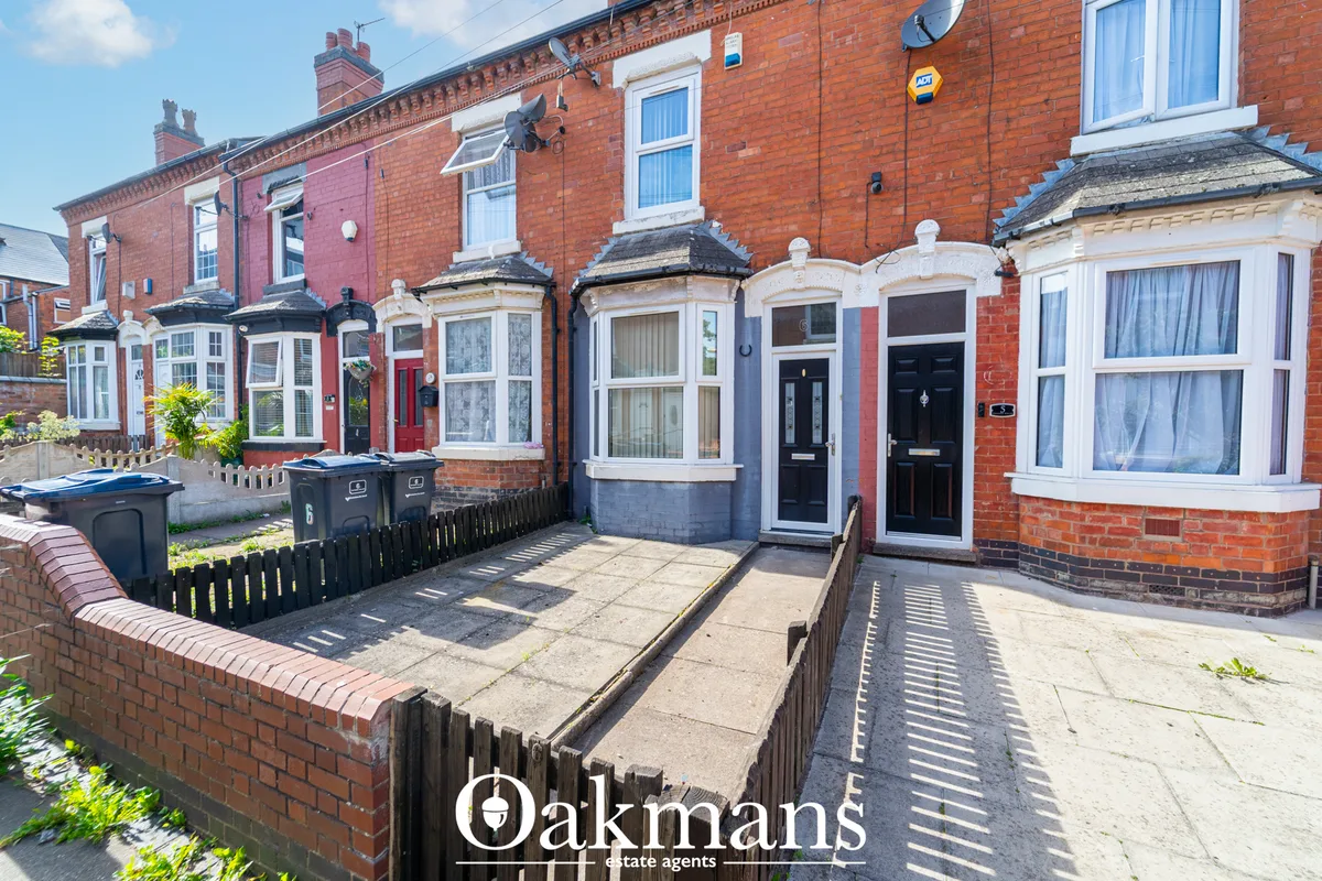 Row of terraced brick homes with varied colours, bay windows, and front yards with low fencing
