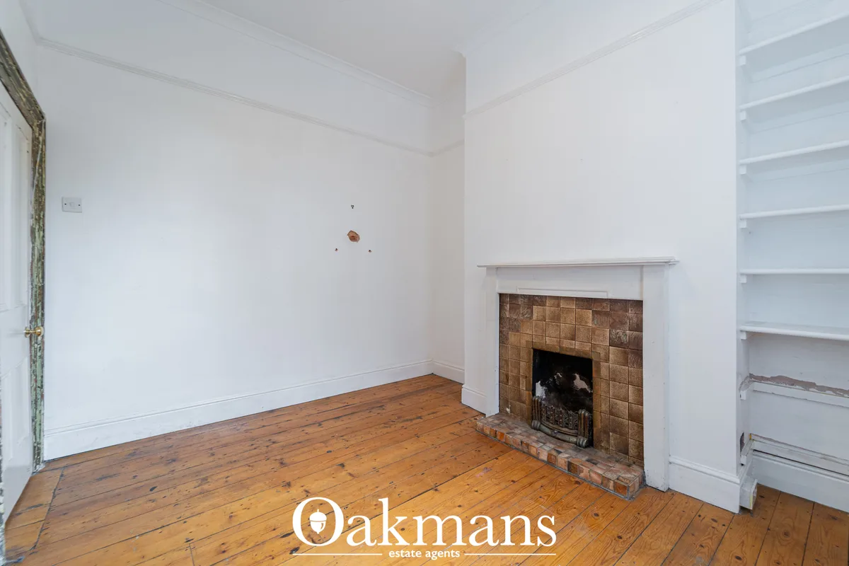 Bright living room with wooden floorboards, white walls, fireplace with brown tiles, white mantelpiece, built-in shelvin