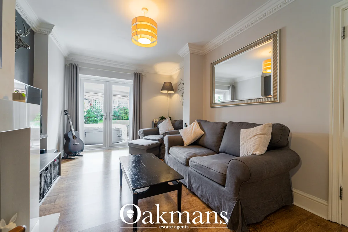 Contemporary living room with grey upholstered sofa, black coffee table, framed mirror, pendant lighting and French door