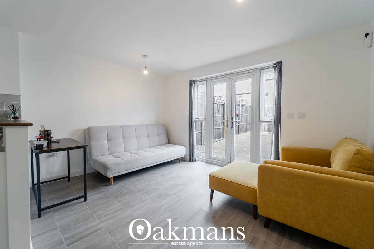 Bright living room with grey sofa, mustard armchair, desk, wooden flooring and bi-fold doors opening to terrace