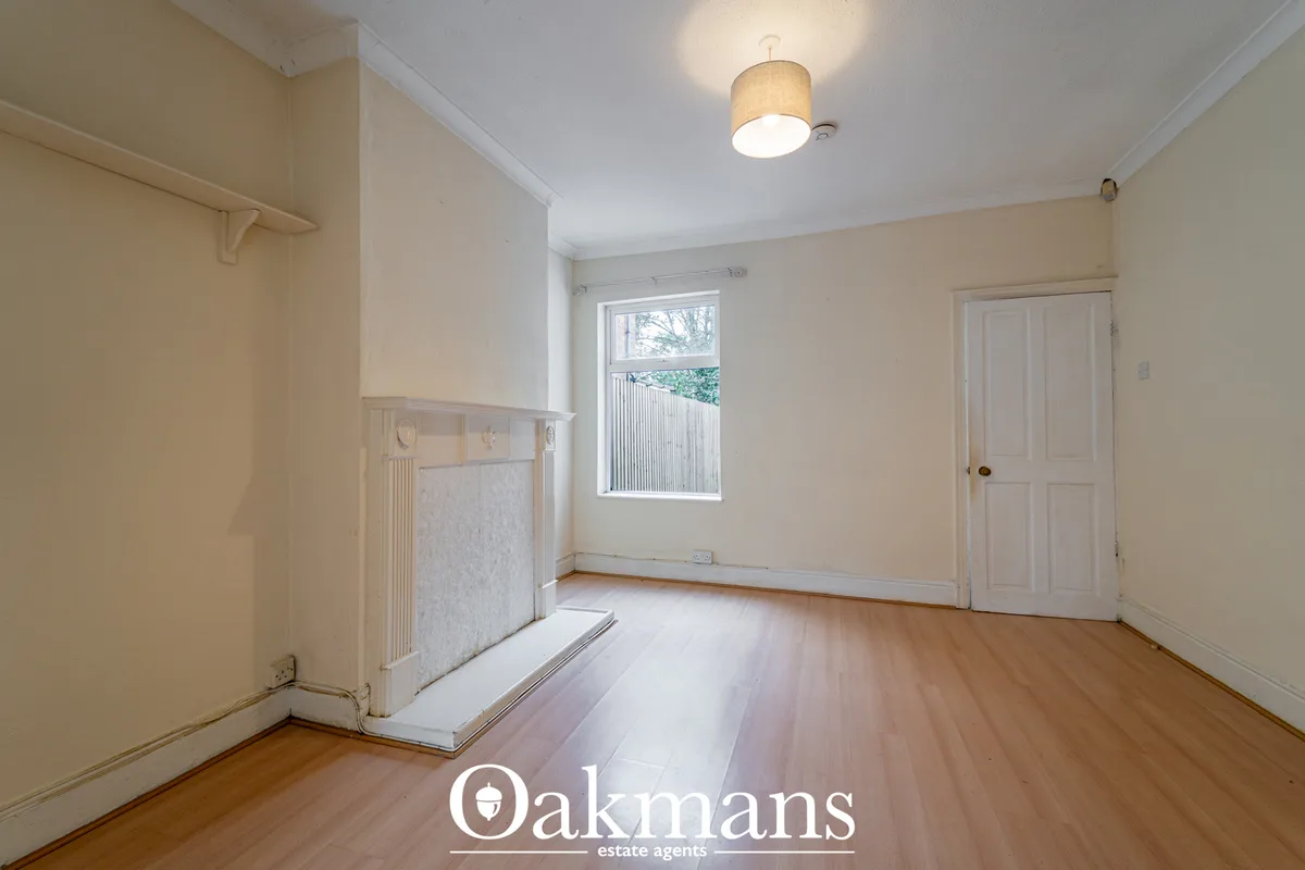 Spacious bedroom with wooden flooring, cream walls, window with blinds, ceiling light fixture, radiator and white panell