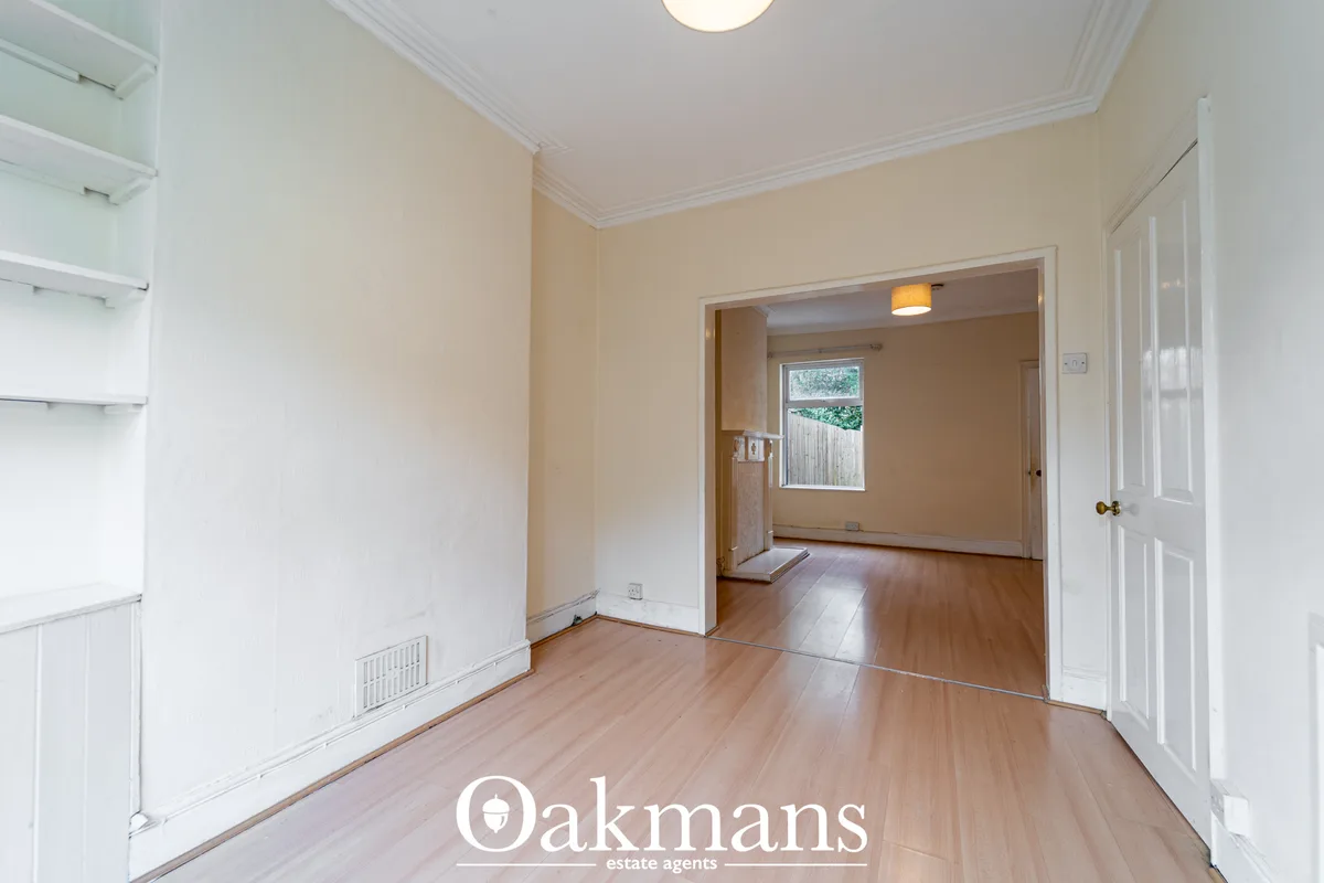 Bright entrance hallway with cream walls, wooden flooring, white ceiling coving and connecting doorways to adjacent room